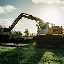 Ein Bagger bei der Arbeit mit der untergehenden Sonne im Hintergrund.