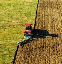 Luftbild von einem roten Bagger auf dem Feld